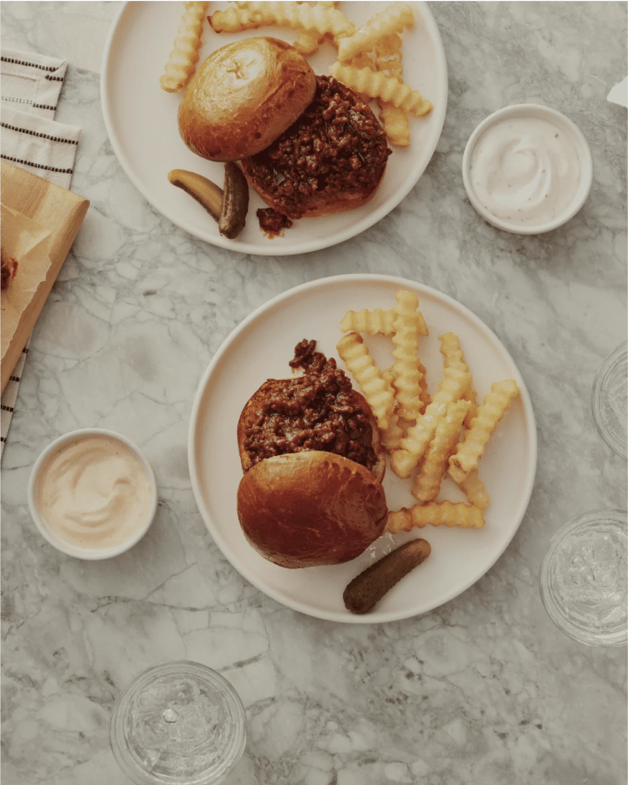 sloppy joes and french fries on plates with a marble background